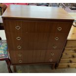 A teak chest with a rectangular top above five drawers on square legs