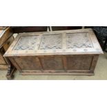 An 18th century style oak coffer with a carved three panel top above a three pane front on stiles