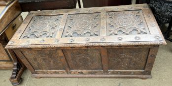 An 18th century style oak coffer with a carved three panel top above a three pane front on stiles