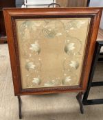 A mahogany framed fire screen with central embroidered panel on shaped feet