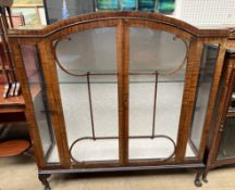 A 20th century walnut display cabinet with an arched top above a pair of glazed doors,