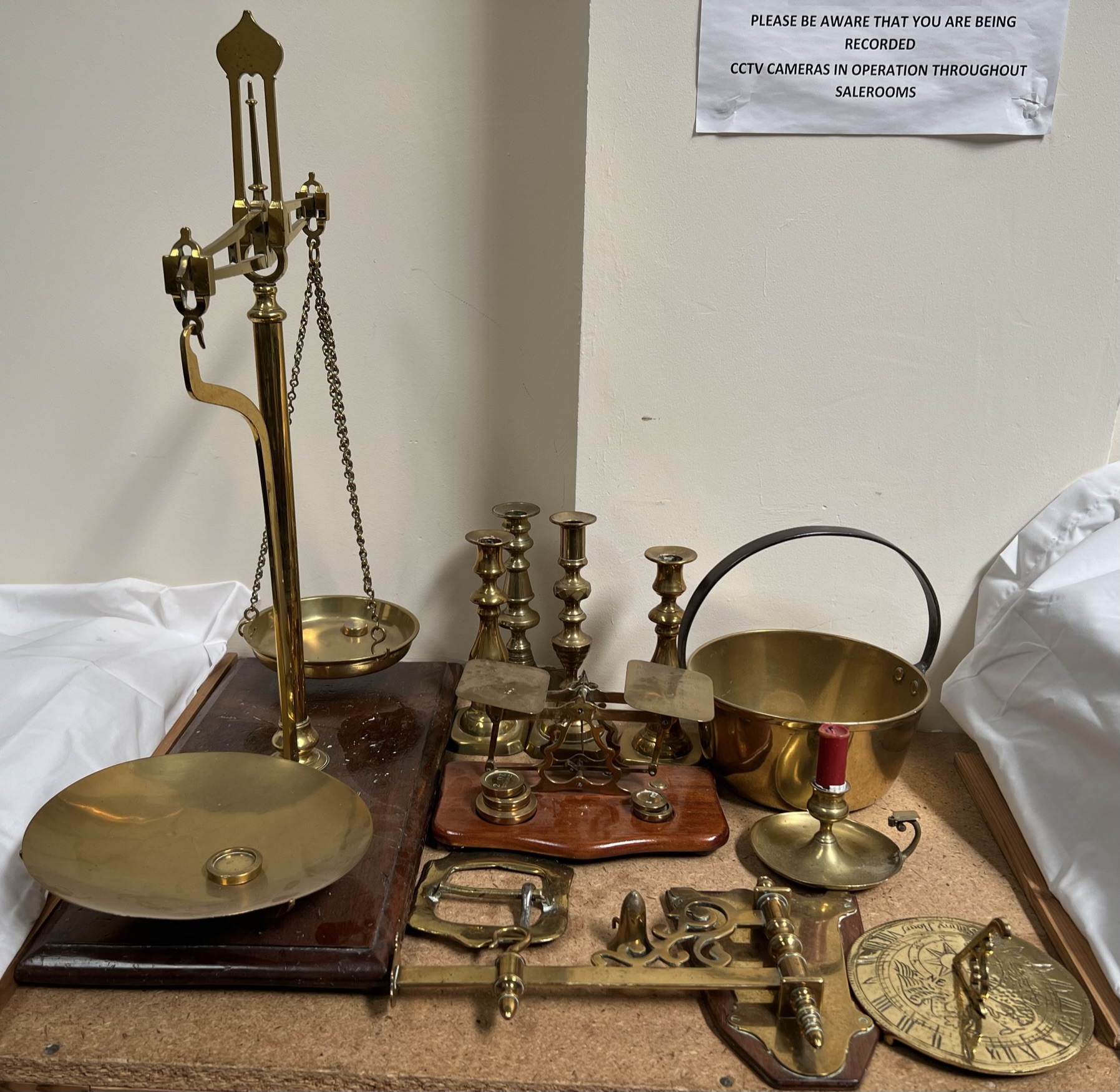 A brass balance beam scales together with brass candlesticks, brass letter scales, brass sundial,