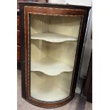 An Edwardian hanging corner cabinet, with a moulded cornice above a bowed glass door,