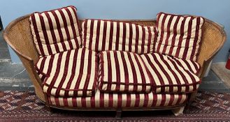 A carved bergère three seater settee with curved sides on square legs