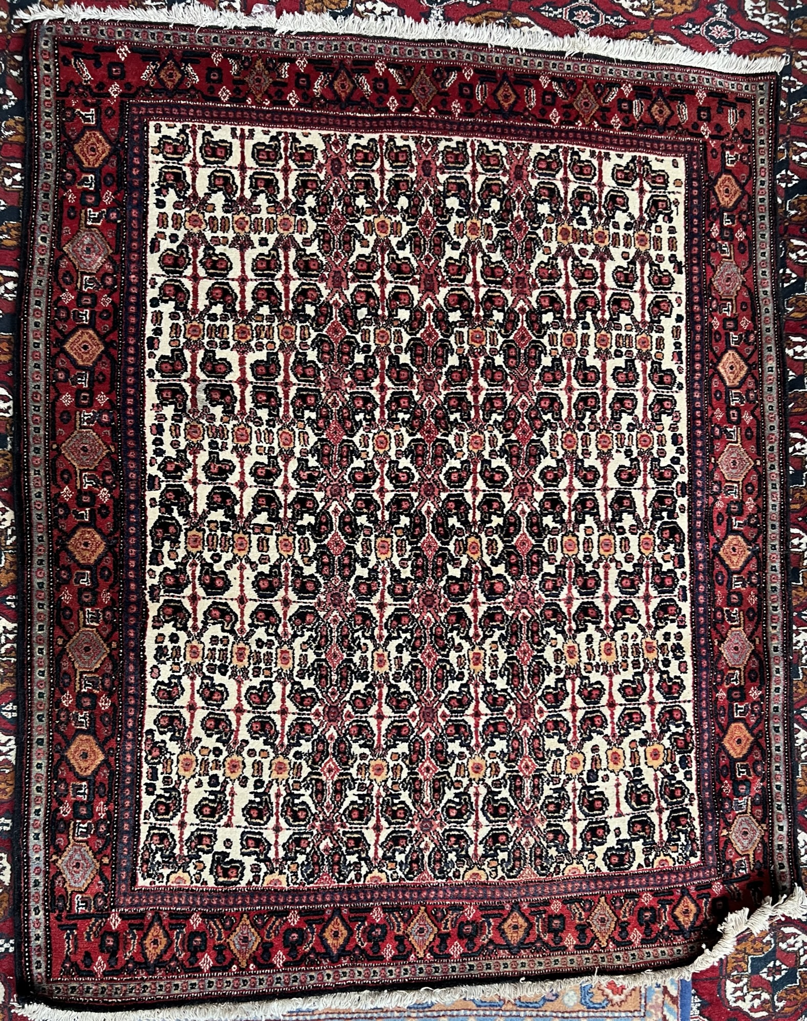 A rug with a cream ground the centre decorated with stylised flowers to a red border,