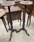 A pair of mahogany torcheres with circular tops above a tapering reeded column in a tripod base