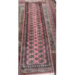 A Pakistani Bokhara wool pile rug with a pink ground and multiple guard stripes,