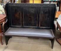 An ebonised oak settle with a three panel back above a pad seat on stiles
