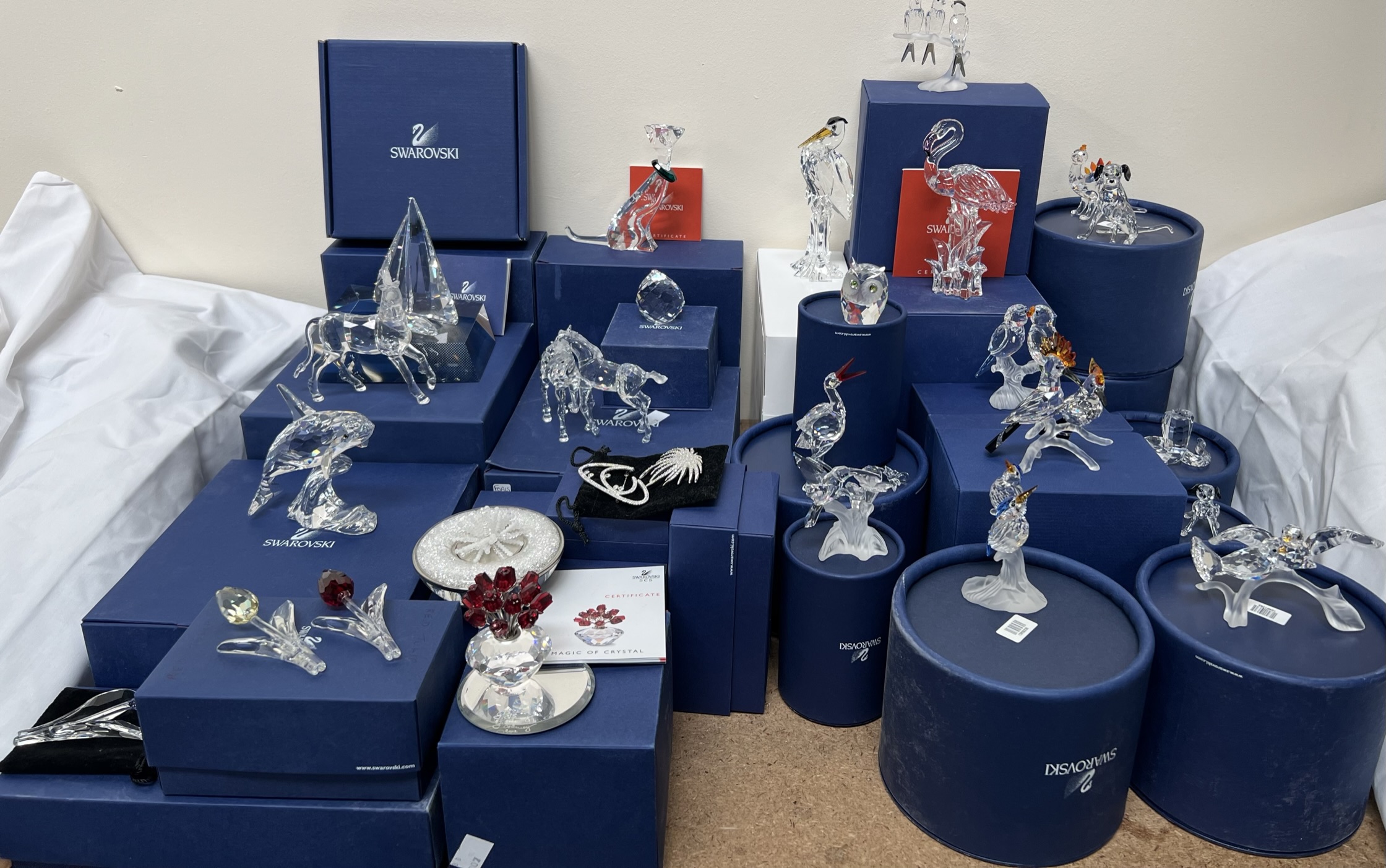 A large collection of Swarovski figures including a sailing ship, horses, whale, flowers, stork,