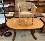 A teak dining table together with a wicker chair and a standard lamp