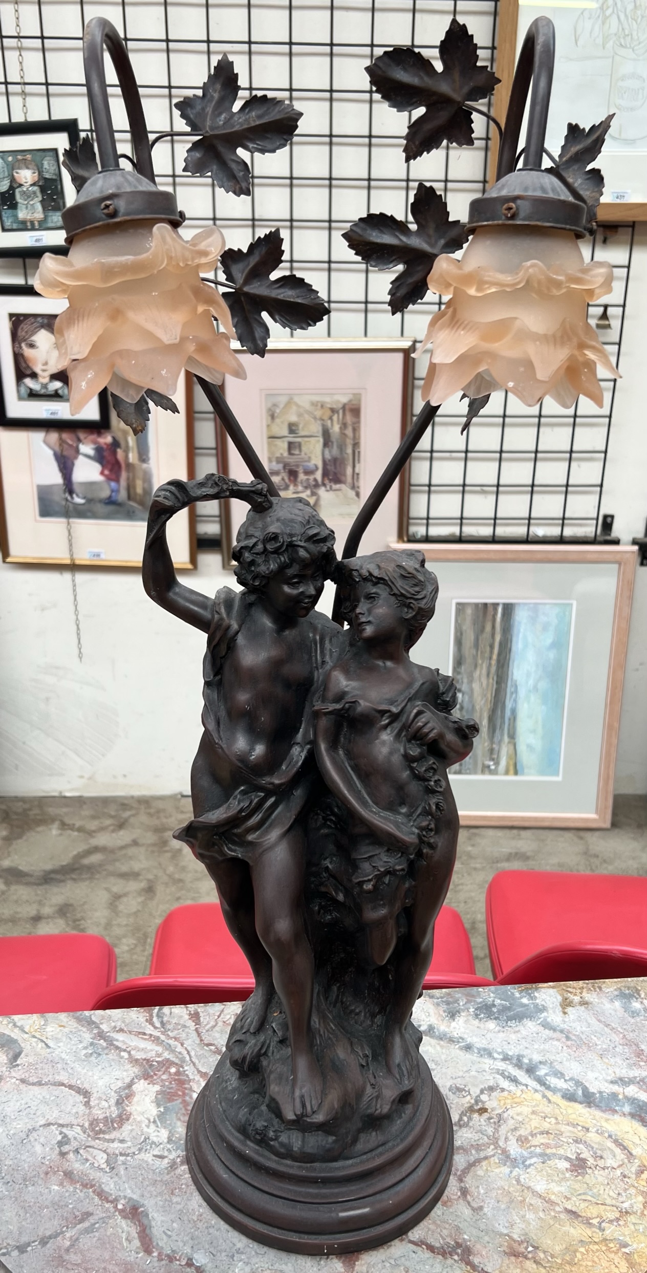 A bronzed figural table lamp depicting two lovers under bowers with glass lamp shades