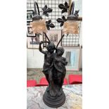 A bronzed figural table lamp depicting two lovers under bowers with glass lamp shades