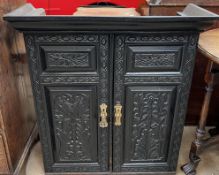 A 19th century carved ebonised bookcase top with a pair of carved doors