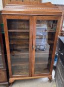 A 20th century oak display cabinet with a caddy top and a pair of glazed doors on cabriole legs and
