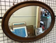 An oak famed wall mirror of oval form with a gadrooned edge