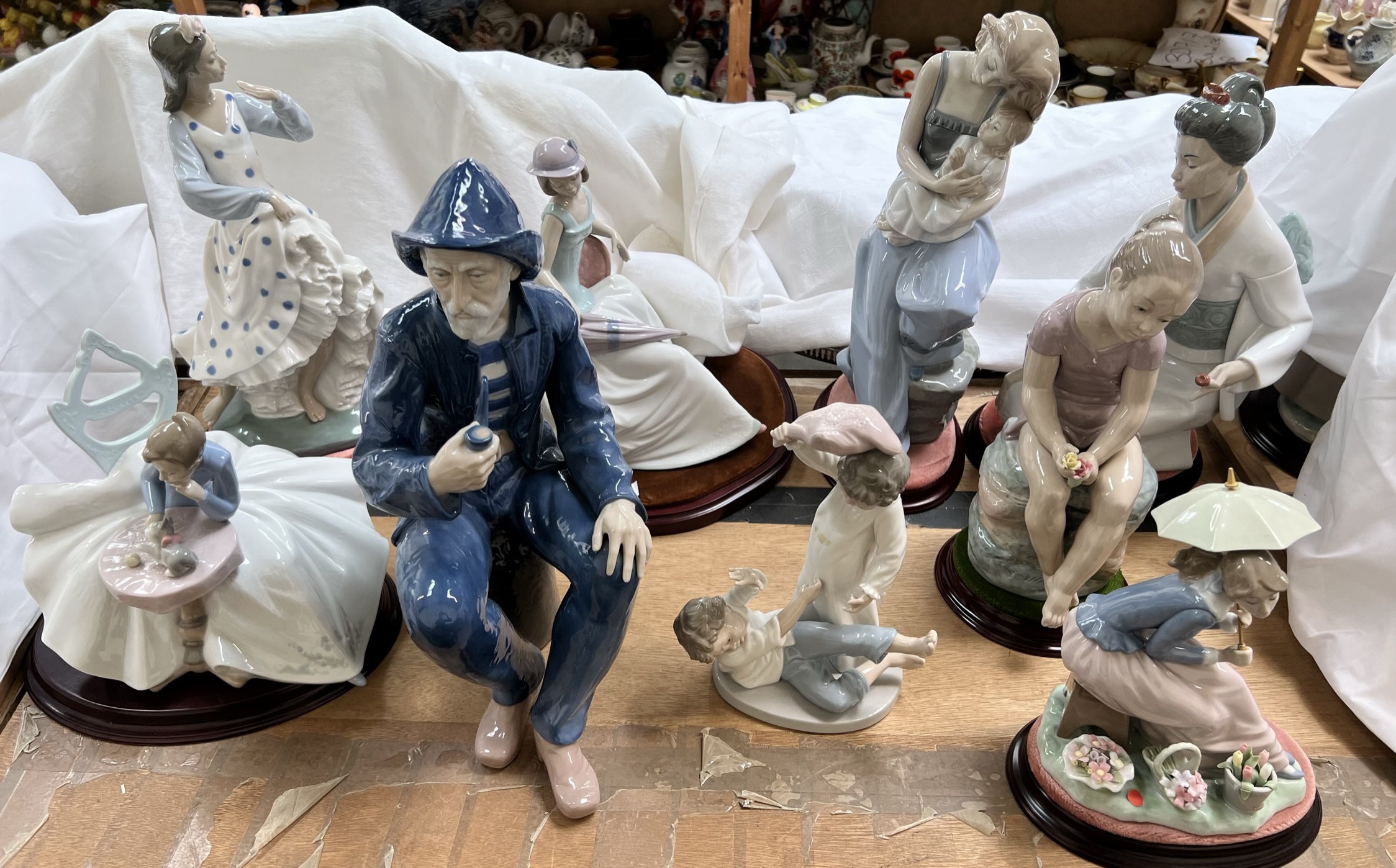 Various Nao porcelain figures including a fisherman smoking a pipe, young lady and kitten,