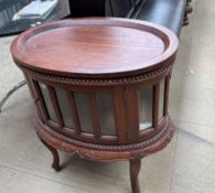 A 20th century mahogany drinks cabinet of oval form with tray top above a glazed door and sides on