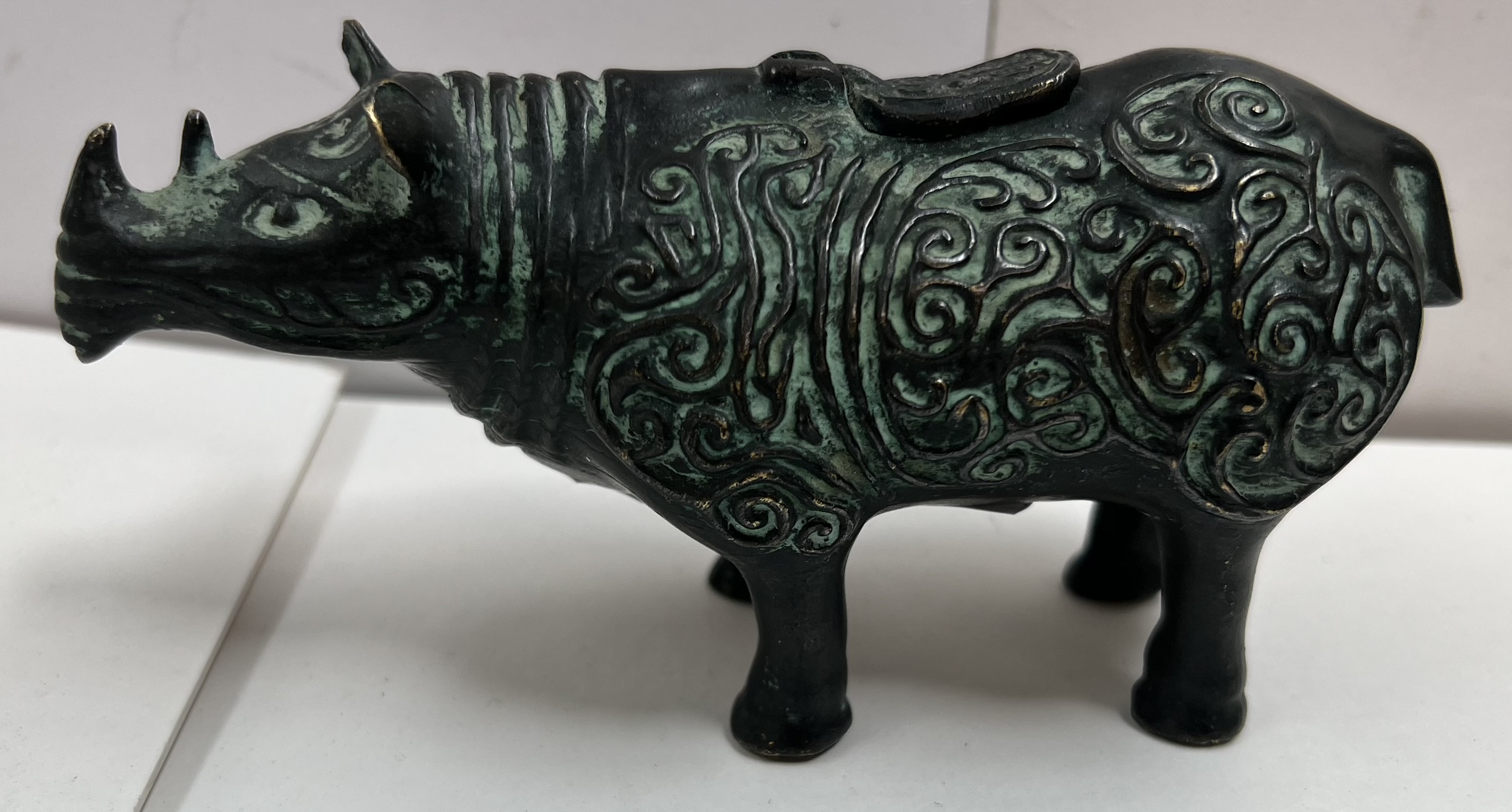 A Zhou style bronze rhinoceros, with scrolling decoration,