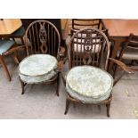 A pair of Ercol elbow chairs with prince of wales feathers splat back on outswept legs