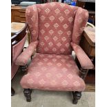 An early 20th century upholstered wing back elbow chair on cup and cover legs