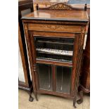 A late Victorian rosewood music cabinet with a shaped back above a glazed door with shelves and