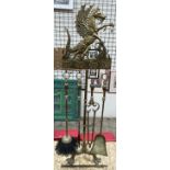 A brass fireside tidy with a dragon surmount and four tools and three legs and claw feet,