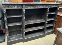 A 19th century carved oak breakfront bookcase carved with leaves, masks and fruit,