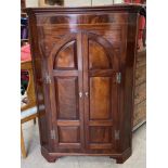 A 19th century mahogany standing corner cupboard with a moulded cornice above a pair of arched