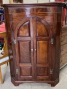 A 19th century mahogany standing corner cupboard with a moulded cornice above a pair of arched