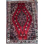 A Hamadan rug with a red ground with wheel decorated spandrels and guard stripes,