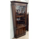 A reproduction mahogany standing corner cupboard with a moulded cornice above a glazed door and two