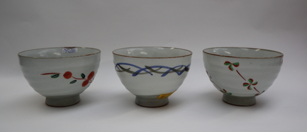 Three assorted stoneware footed bowls in the Chawan style, decorated with flowers and lines,