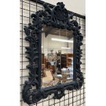 A wall mirror with a leaf and scrolling border in black