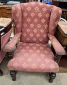 An early 20th century upholstered wing back elbow chair on cup and cover legs