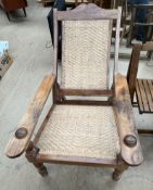 A Chinese hardwood steamer chair with a sloping back and basket weave back and seat