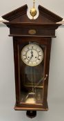 A 20th century mahogany wall clock with a broken swan neck pediment and glass door with circular