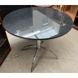 A granite topped dining table of circular form on a chrome base