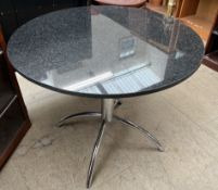 A granite topped dining table of circular form on a chrome base