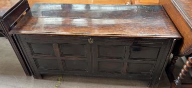 An 18th century and later oak coffer with a planked rectangular top above a panelled front on
