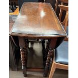 An early 20th century oak gateleg dining table with an oval top with drop flaps on barley twist