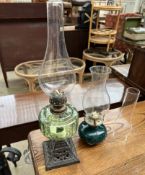 A Victorian green glass oil lamp together with another oil lamp and a wrought iron standard lamp