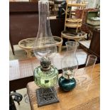 A Victorian green glass oil lamp together with another oil lamp and a wrought iron standard lamp