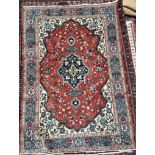 A rug with a central red medallion and interlaced flowers with cream ground spandrels and multiple