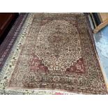A room size rug with a central medallion of flower head and leaves to a cream ground with spandrels