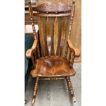 A modern rocking chair with a carved back rail and slats on a solid seat and rocker base