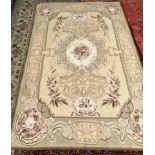 A rug with a cream ground and central floral panel, the edges decorated with flowers and leaves,