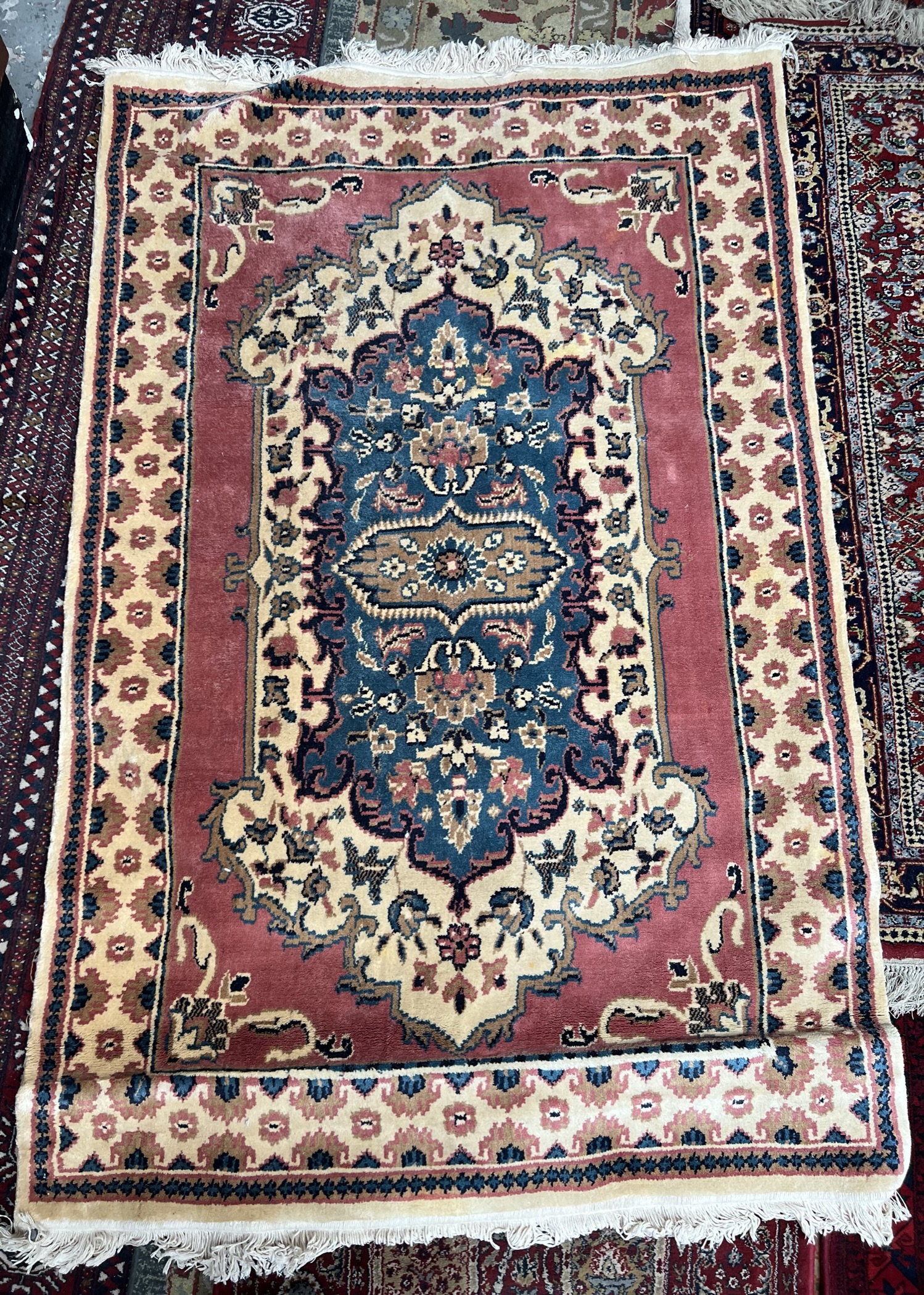 A rug with a central blue medallion, rose pink border and multiple guard stripes,