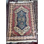 A rug with a central blue medallion, rose pink border and multiple guard stripes,
