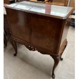 A 20th century walnut cocktail cabinet with a rectangular top above a pair of drawers on a carved