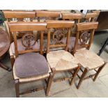 A set of six dining chairs with a bar back and roundel with floral centre and a rush seat on